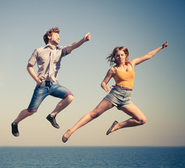 Fototapeta na wymiar Carefree couple jumping by sea ocean water.