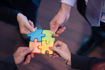 top view of business people group assembling jigsaw puzzle