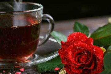 Tea in a transparent cup, color candies and a red rose
