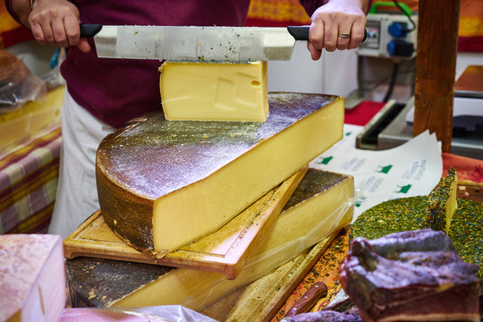 Man cutting slices of delicious cheese / Food market with abundance of high quality cheese