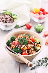 Quinoa salad with broccoli,sweet potatoes and tomatoes on a rustic wooden table.Superfoods concept.Selective focus. 