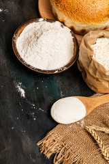 Freshly baked bread and flour in rustic dark background.