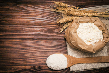 Wheat ears and flour  on rustic wooden table