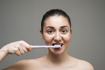 Young beautiful girl with toothbrush on the gray background