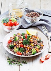 Quinoa salad with broccoli,sweet potatoes and tomatoes on a rustic wooden table.Superfoods concept.Selective focus