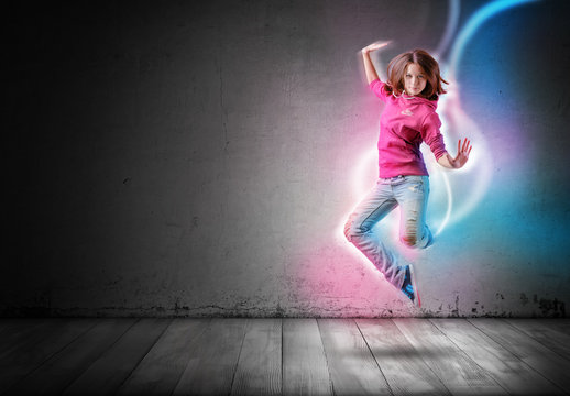 Modern girl jumps and dances with glowing light lines following her move on dark background