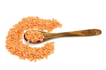 Löffel aus Olivenholz mit ungekochten roten Linsen isoliert auf weißem Hintergrund