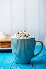 Blue ceramic cup of coffee with whipped cream