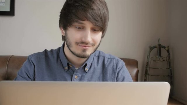 Happy Young Man Freelancer with Modern Laptop in Cafe taking Cup of Coffee