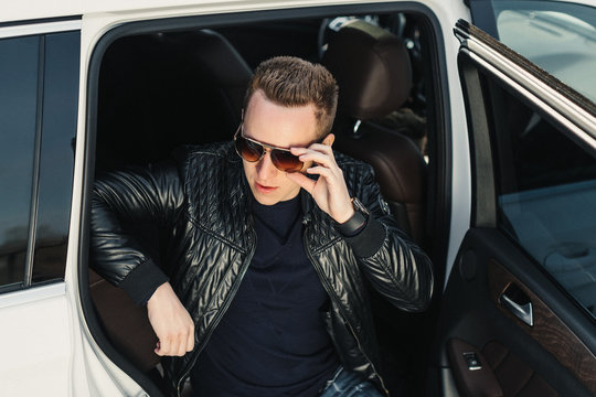 Portrait Fashionable Handsome Man in Sunglasses Sitting in rear Seat with open door. Luxury Life. Lifestyle photo. Ideal for commercial. 