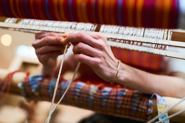 Hands engaged in production of handicraft textiles on the loom