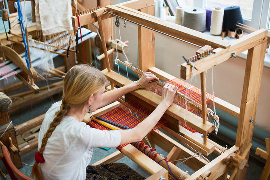 The girl in the production process of textiles are handmade on a loom