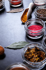 Spices on black background in special jars. Food