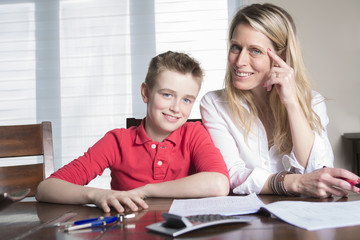 mother at a table at home helping her small son with his homework