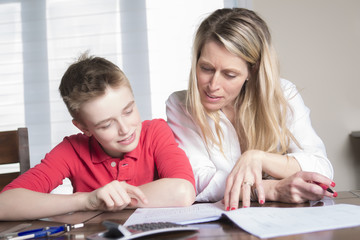 mother at a table at home helping her small son with his homework