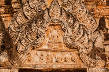 Floral patterns and Buddha figures on stone relief of ancient temple in Thailand