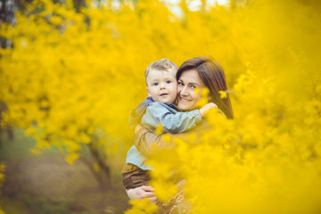 Mother and son happy in the park, near yellow flowers
