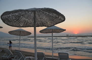 White reed parasols at sunset on the beach of a hotel on the Turkish coast close to Kusadasi