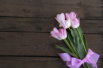 Beautiful bouquet of pink tulips on dark wooden background