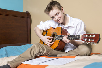 teenage boy playing guitar in her bedroom