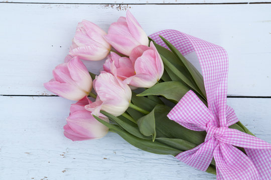Beautiful bouquet of pink tulips on light wooden background
