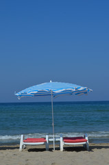 Deckchairs and colourful parasols on the beach at the Turkish Riviera close to Kusadasi