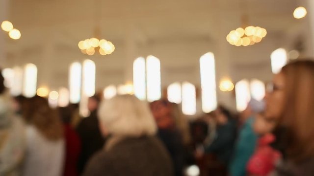 People pray in the church. The image is blurred.