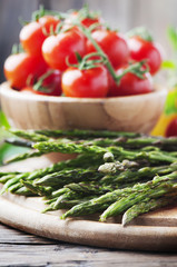 Raw asparagus with tomato on the wooden table