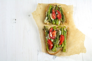 green asparagus, tomatoes and parmesan on roasted bread, from above, copy space