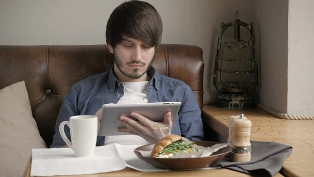 Handsome Young Man Freelancer with Modern Laptop in Cafe taking Cup of Coffee