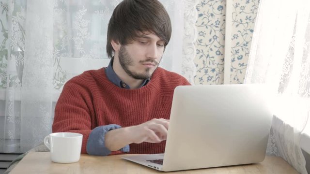 Happy Young Man Freelancer with Modern Laptop in Cafe taking Cup of Coffee