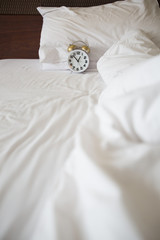white alarm clock and bed
