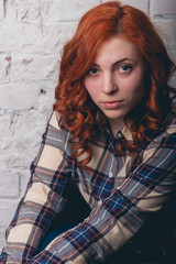 Fototapeta premium Happy young girl sitting over brick wall