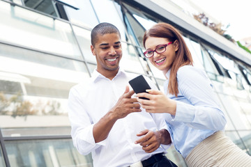 Obraz premium Business couple looking at smart phone and smiling. Shallow depth of field.