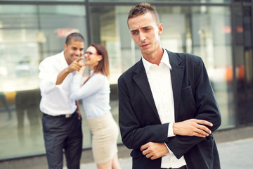 Gossip colleagues in front of their office, businessman portrait and gossiping out of focus in...