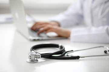 Female doctor typing on laptop, close up