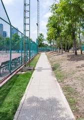 Small walkway beside the tennis court in the urban park.