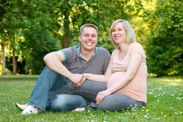 Fototapeta premium Pregnant couple resting in the park