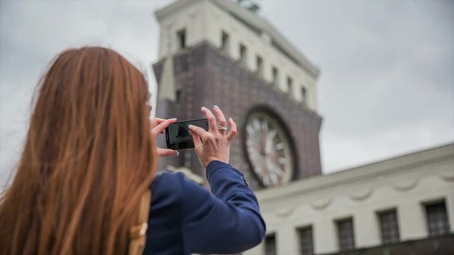 Woman take picture of church with big clock