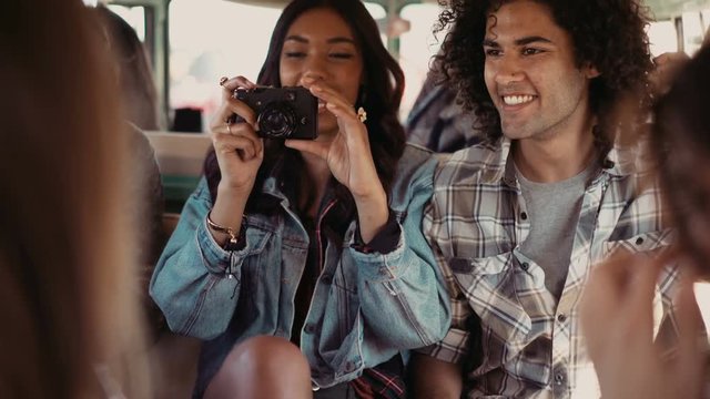 Hipster girl photographing friends in a van during road trip