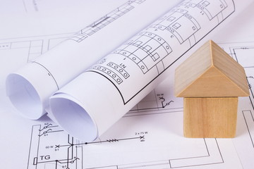 House of wooden blocks and rolls of diagrams on construction drawing of house