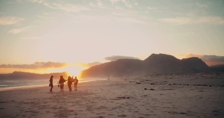 Silhouette of teen friends dancing on the beach at sunset