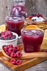 juice of raspberries and blackberries with citrus and pancakes on the table