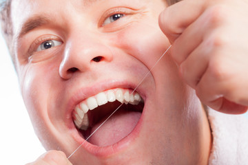 Young man cleaning her white teeth with dental floss