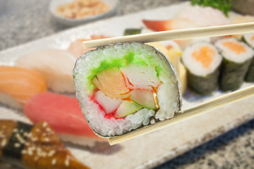 Sushi maki in chopsticks with sushi set