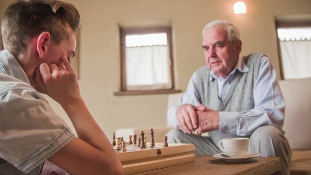 Boy having trouble with chess against elderly person