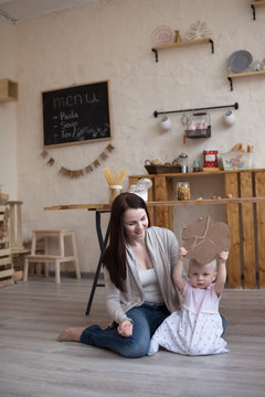 Young mother and toddler daughter drawing  black board and chalk