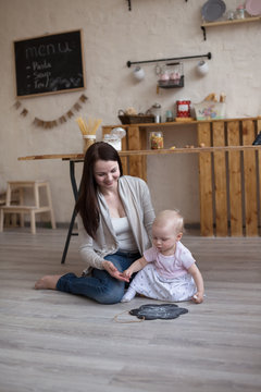 Young mother and toddler daughter drawing  black board and chalk