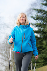 frau geht mit laufstöcken durch den wald