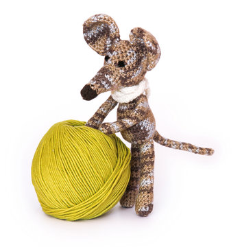 small colorful knitted toy mouse in a white scarf playing with colored yarn, threads of wool, Bright children's toy, clew, knitted mouse between skeins